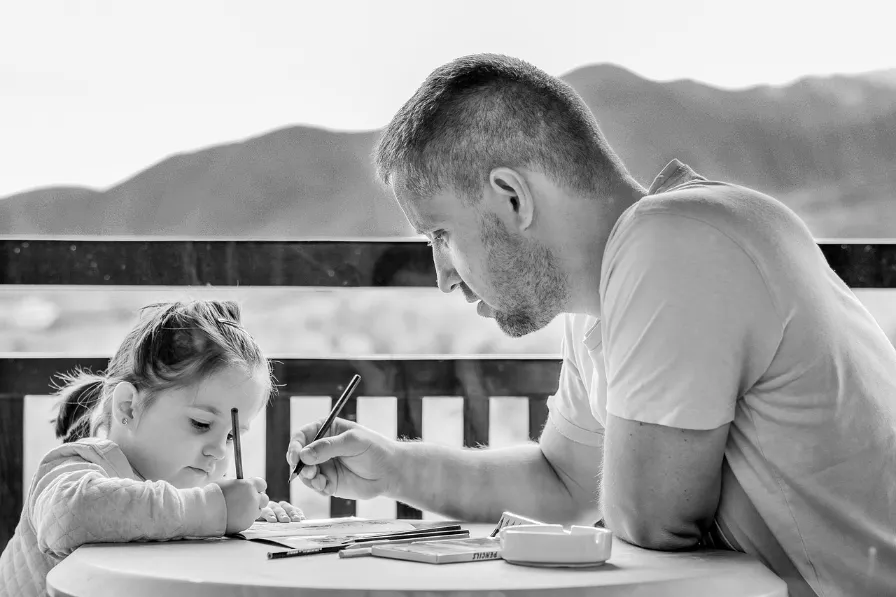 Father and daughter coloring outside.