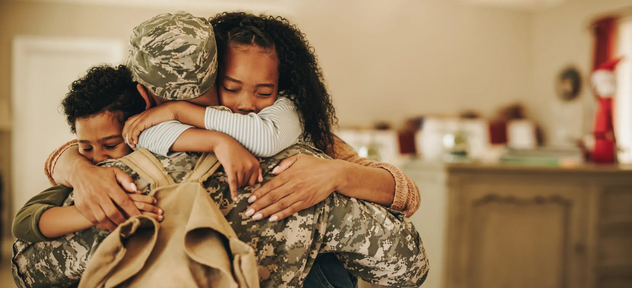 Two kids hugging their dad who is in his military uniform.