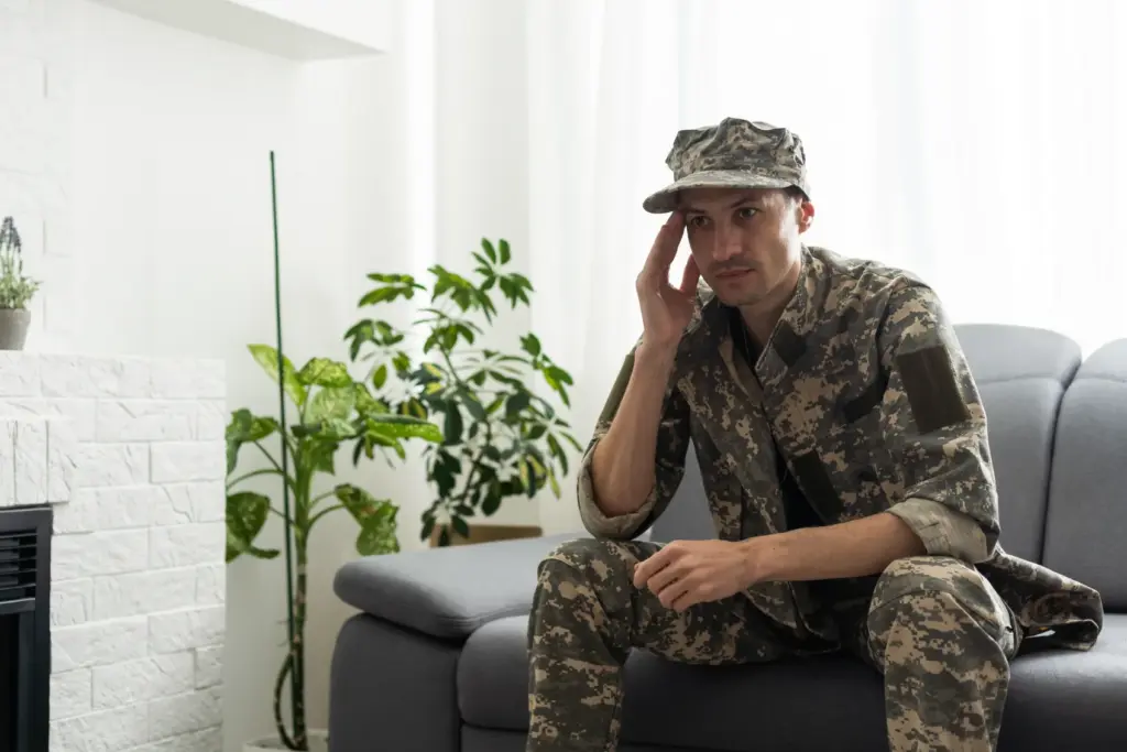A military service member sitting on the couch looking concerned.