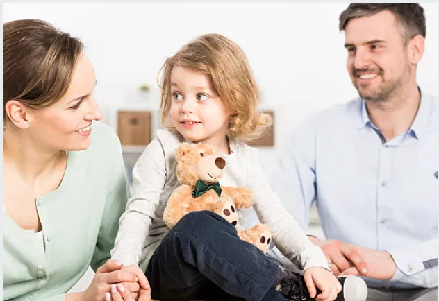 Two parents with their child holding a teddy bear.