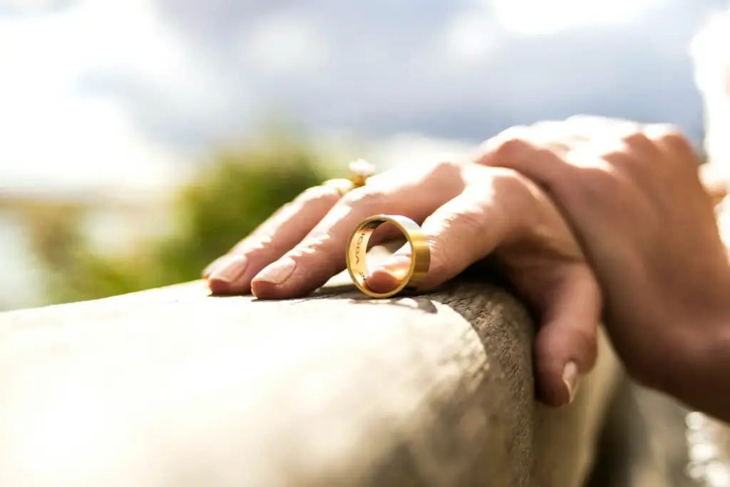 A woman holding her ring in her fingers on a fence.